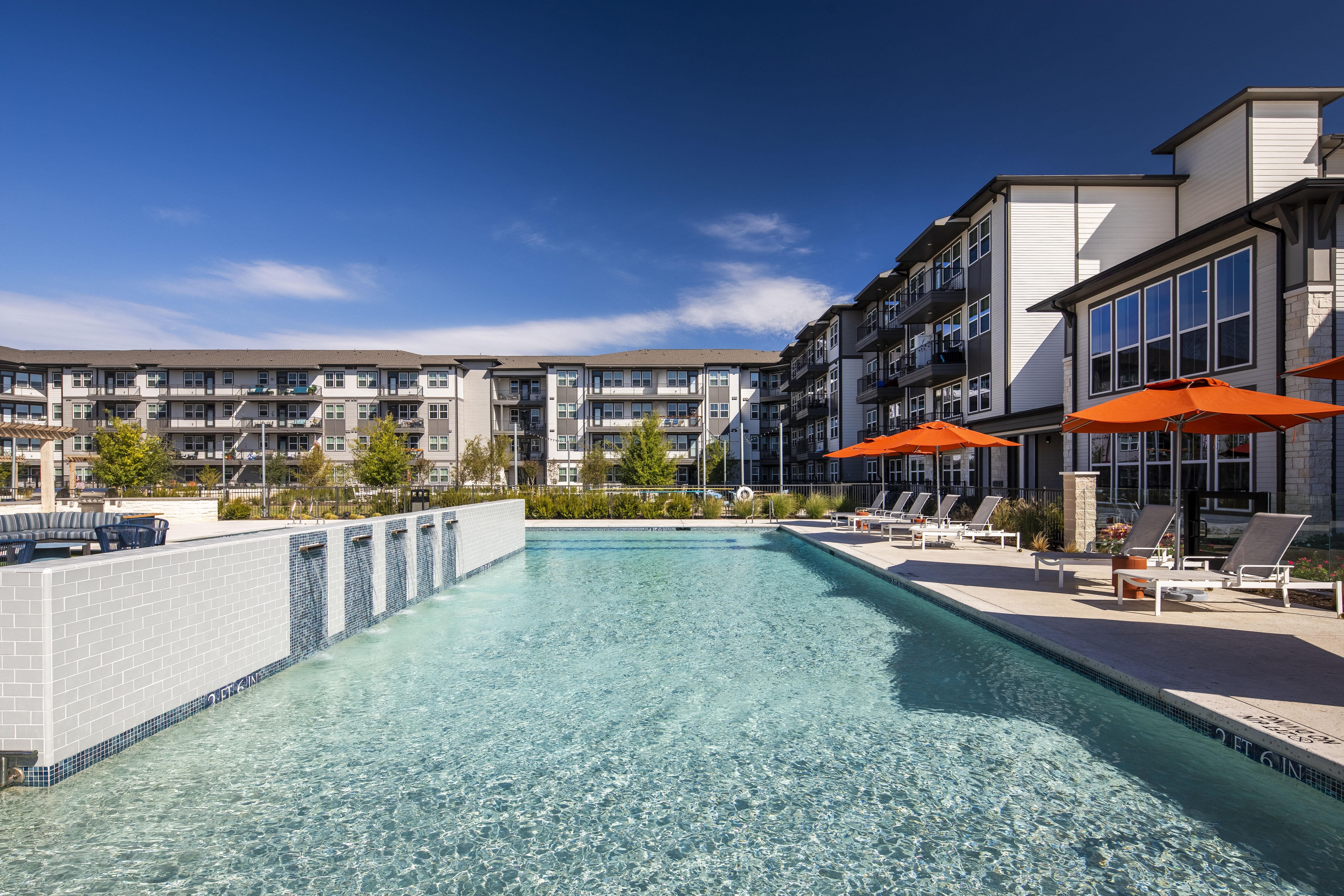 a ground-level view of resort style pool and apartment building at a senior apartment community